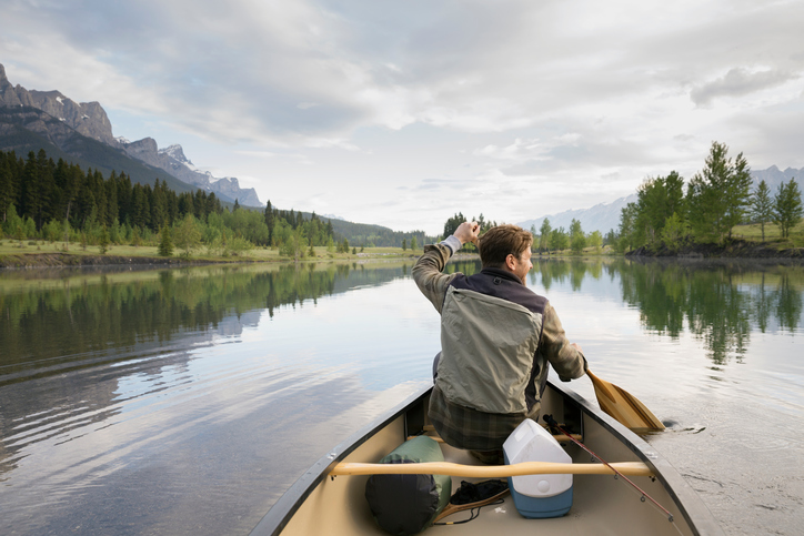 Man rowing canoe in still lake
